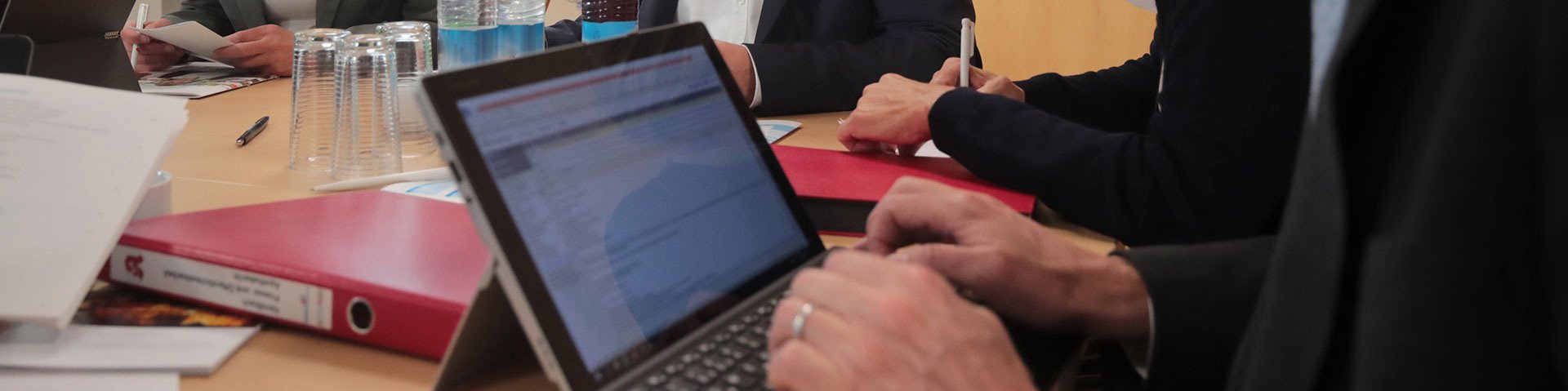 Meeting in der Bayerischen Landesapothekerkammer. Mitarbeiter sind um einen Tisch versammelt. Einer sieht in seinen Laptop. Im Hintergrund steht eine Flipchart.