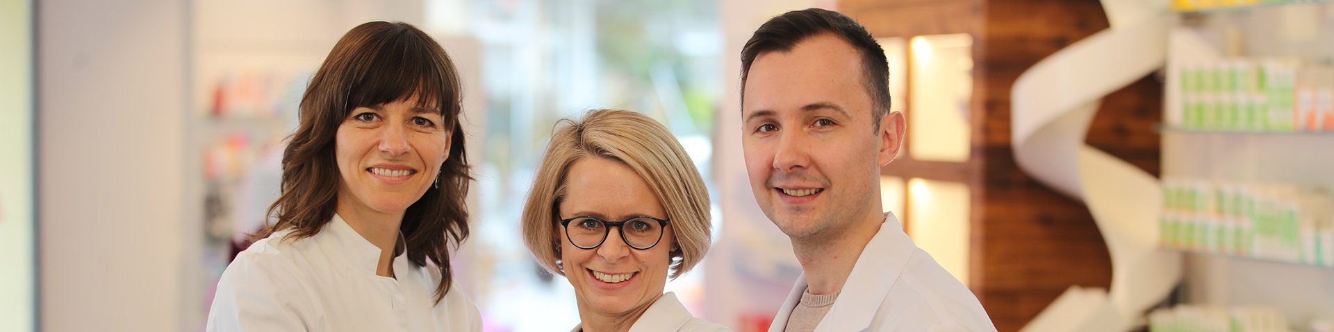 Drei Apotheker der BLAK stehen für ein Gruppenbild nebeneinander in der Apotheke. Auf der rechten Seite steht der Mann und auf der linken Seite die zwei Frauen.